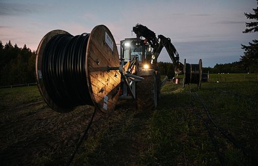 Tractor in the sunset holding a medium voltage cable drum